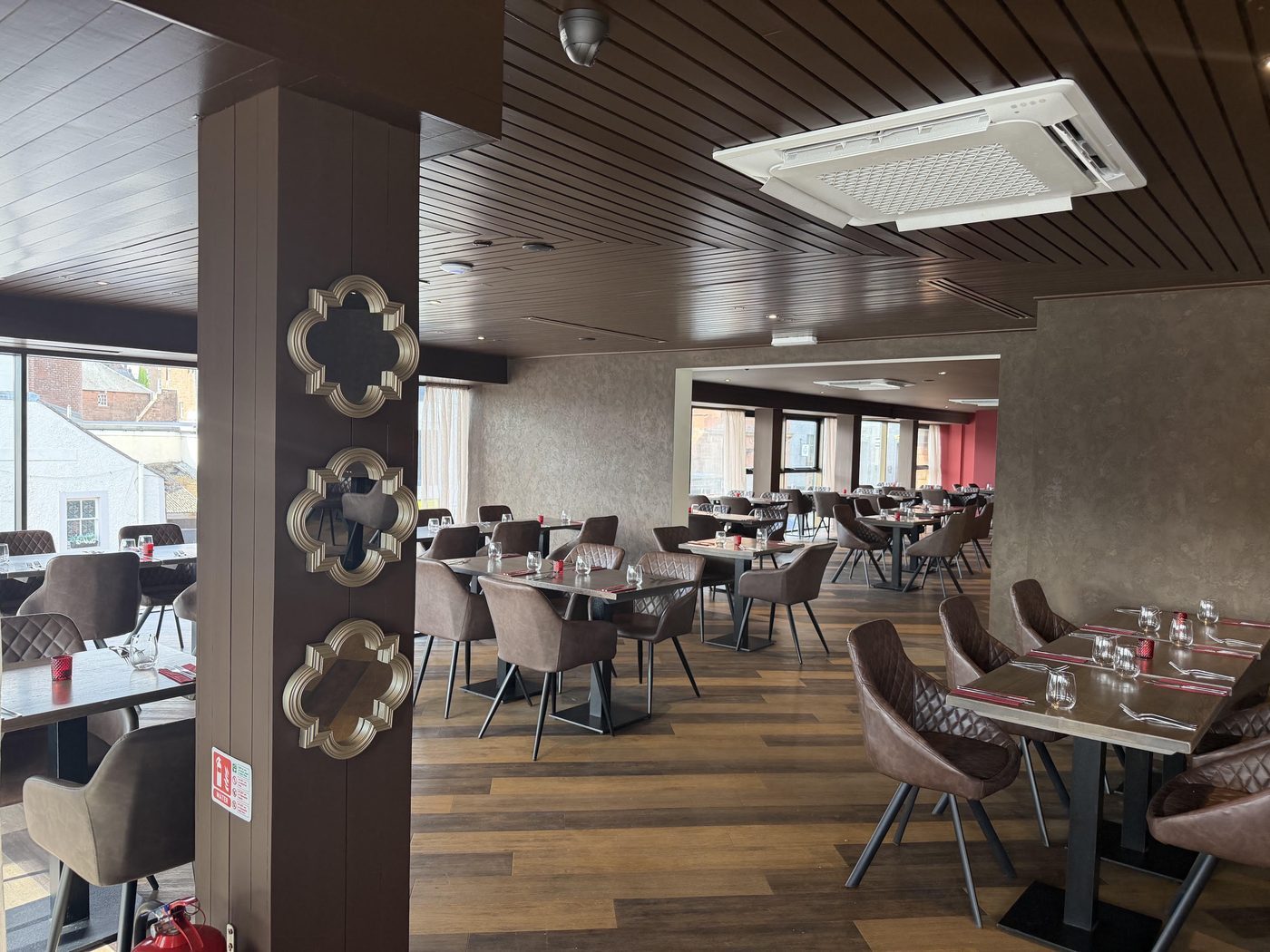 Tables and soft leather chairs running the length of the room, past a panelled pillar hung with gilt mirrors, to a further dining area beyond