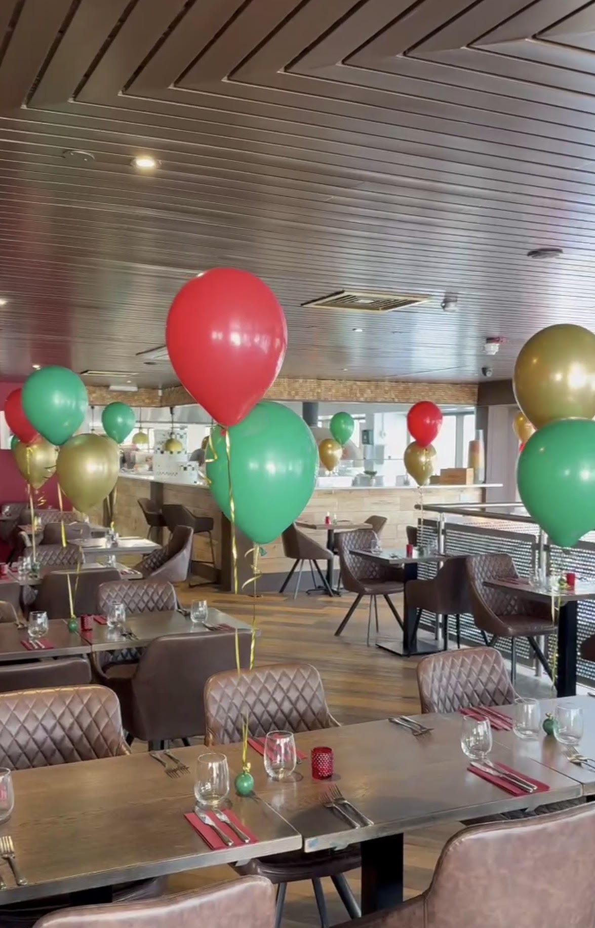 The dining room dressed for opening day, with red, green and gold balloons on the tables
